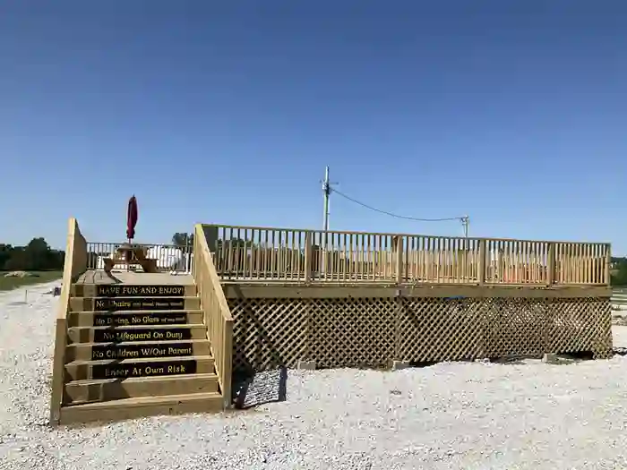 Elevated outdoor wooden deck with seating and umbrella at Highway 54 RV Park in Wheatland MO