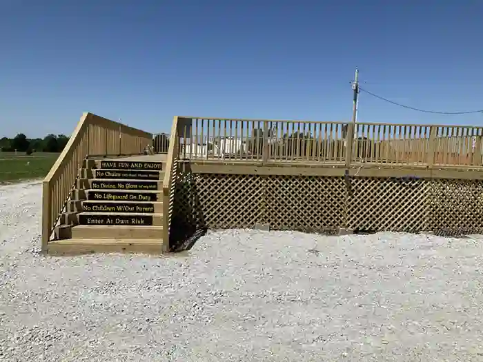 Elevated wooden deck pool area with stairs and safety signs in an outdoor setting