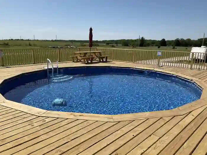 Above ground swimming pool with wooden deck and picnic table at Highway 54 RV Park